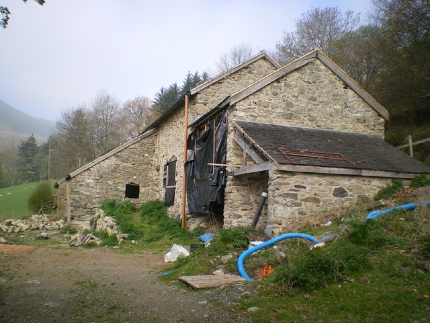 Ancienne grange en cours de transformation avec toiture rénovée et ouvertures de logement